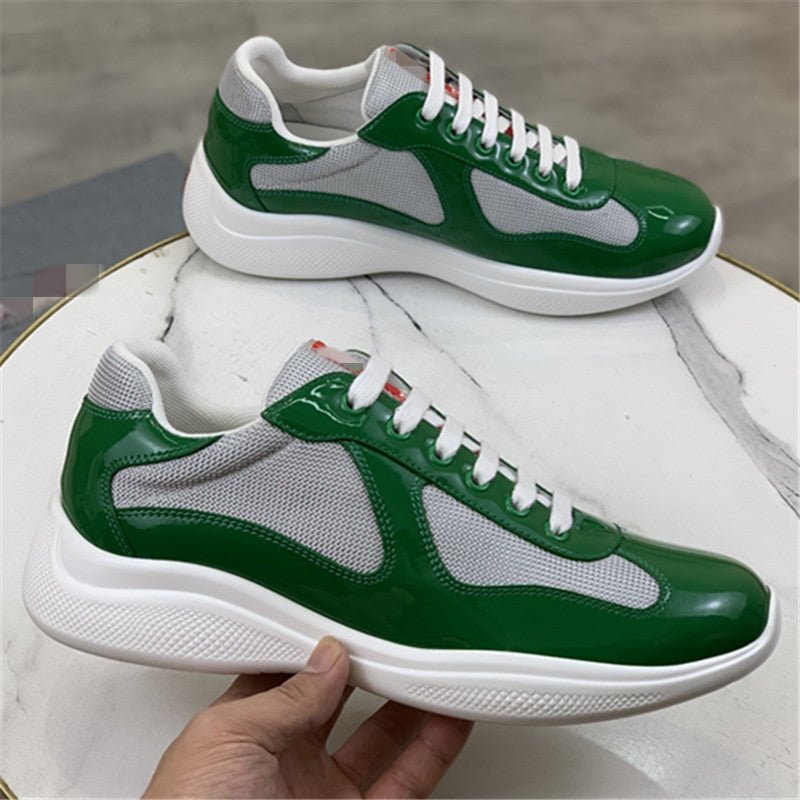 Green and gray sneakers with white laces on a marble surface.