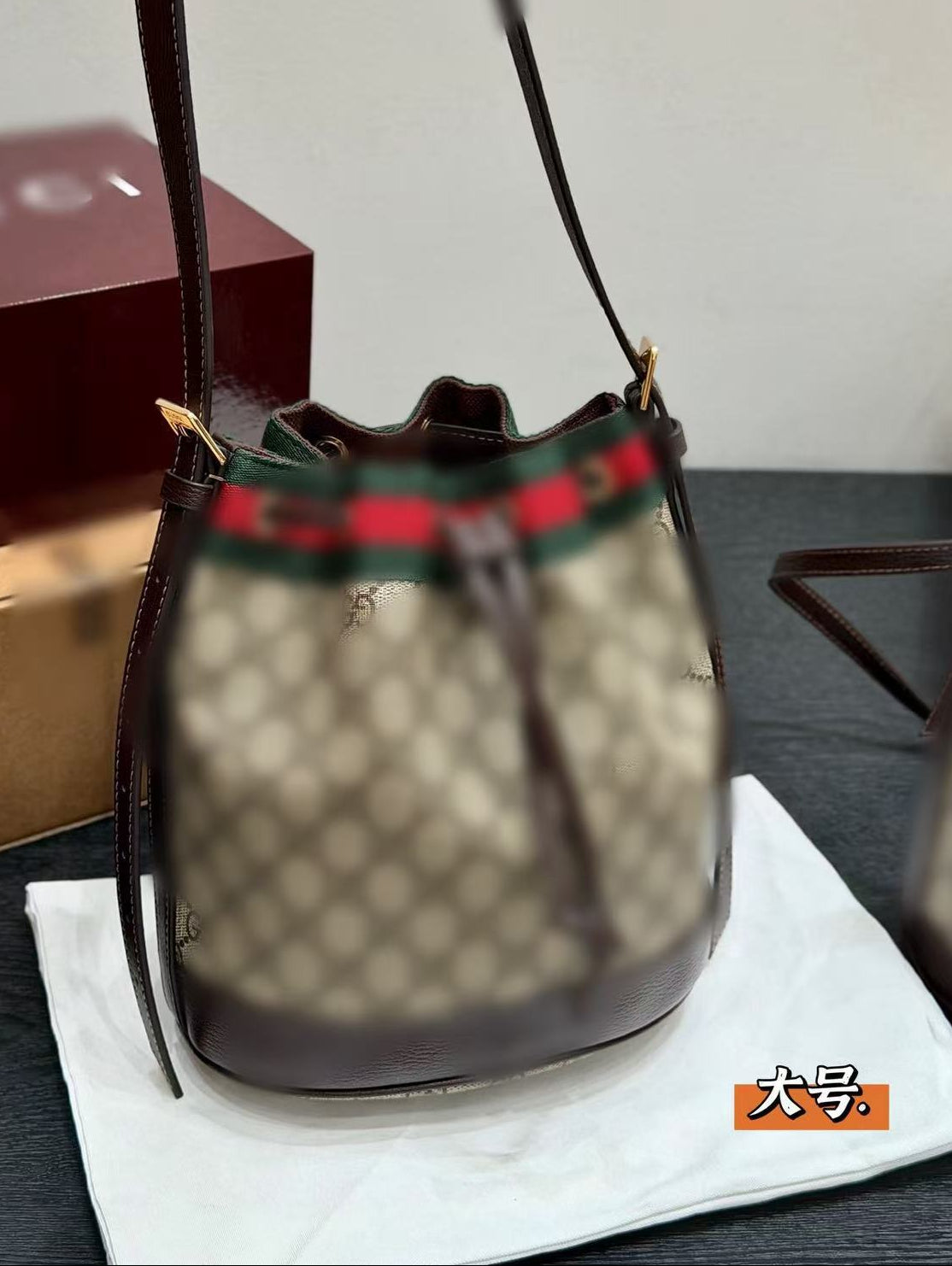 Gucci handbag with distinctive logo on a white surface, with Gucci box in the background.