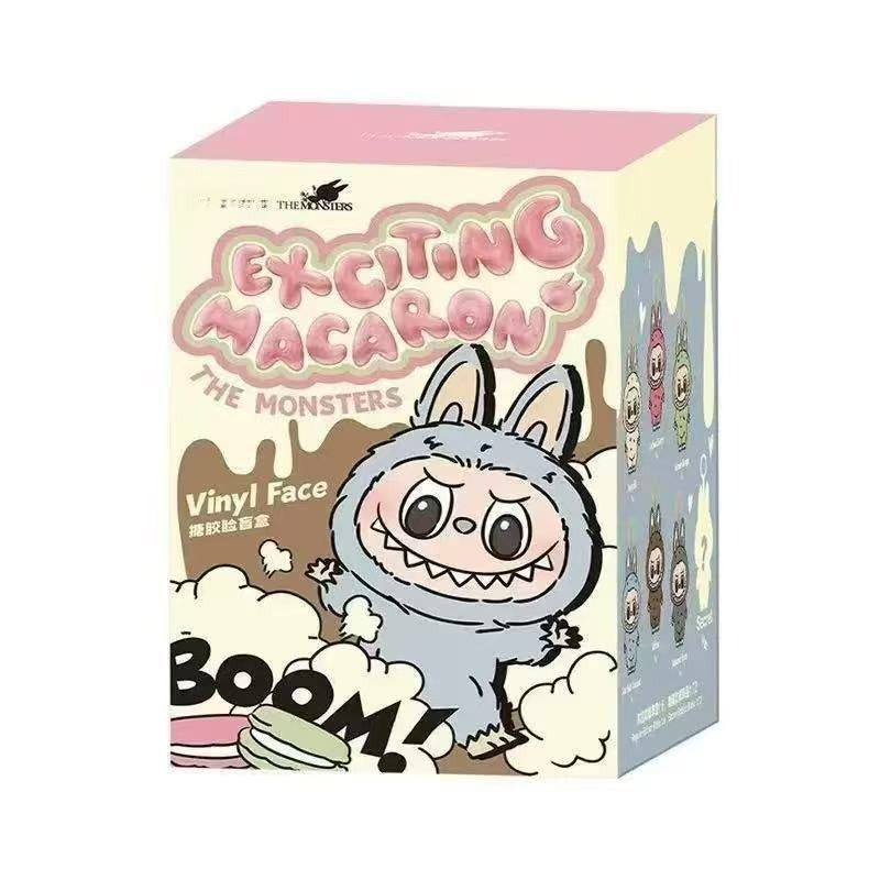 A collectible blind box for 'Exciting Macaron: The Monsters' vinyl face figures by The Monsters. The box features a pastel pink top, a cream-colored front face with a cartoon gray monster character, and a light blue side panel displaying other character options.