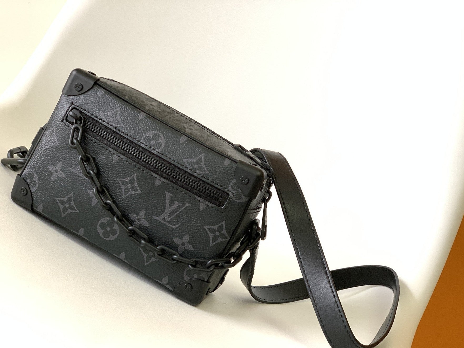 Black patterned Louis Vuitton handbag with a strap on a light background