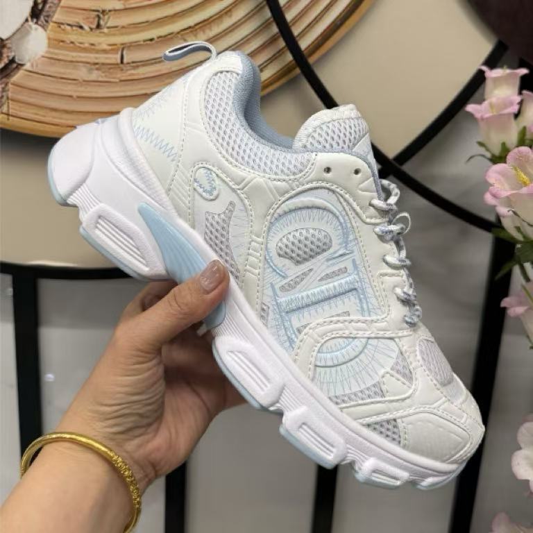 White and light blue sneaker held in a hand with a blurred background