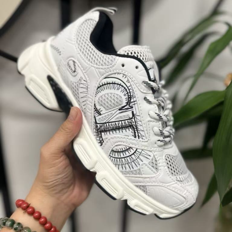 White sneaker with black detailed design held by a hand, blurred background