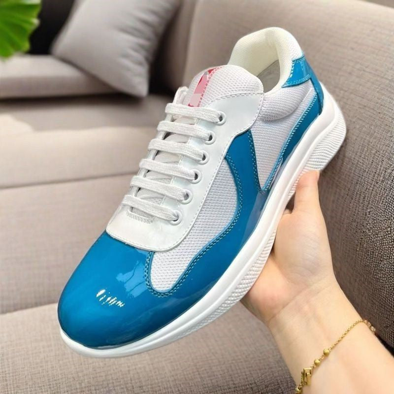 White and blue sneaker held in a hand with a neutral background