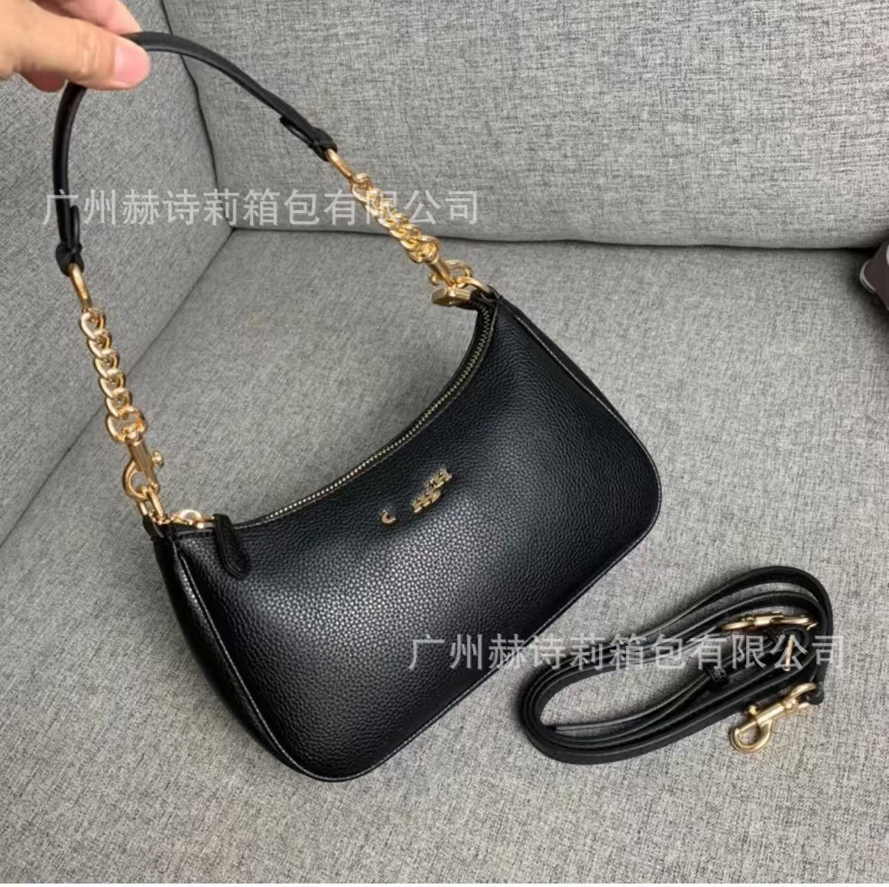 Black handbag with gold chain strap on a gray surface