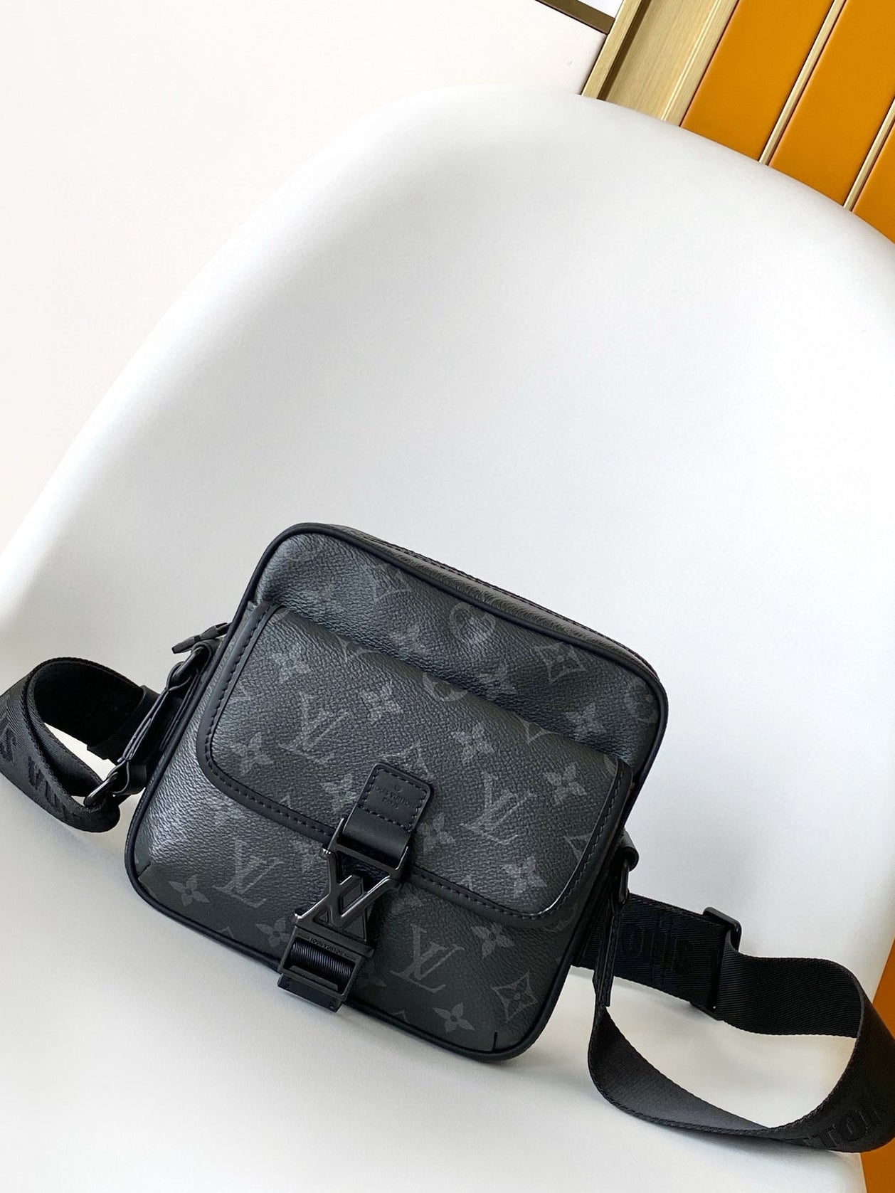 Black patterned bag on a white chair with a yellow wall background