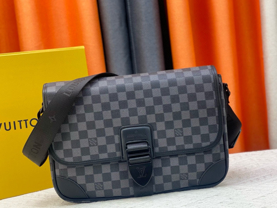 Gray checkered Louis Vuitton bag on a white surface with colorful curtains in the background.
