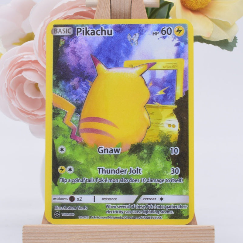 A Pokémon Trading Card Game Pikachu Basic card displayed upright on a small wooden stand, with pink and yellow flowers blurred in the background.