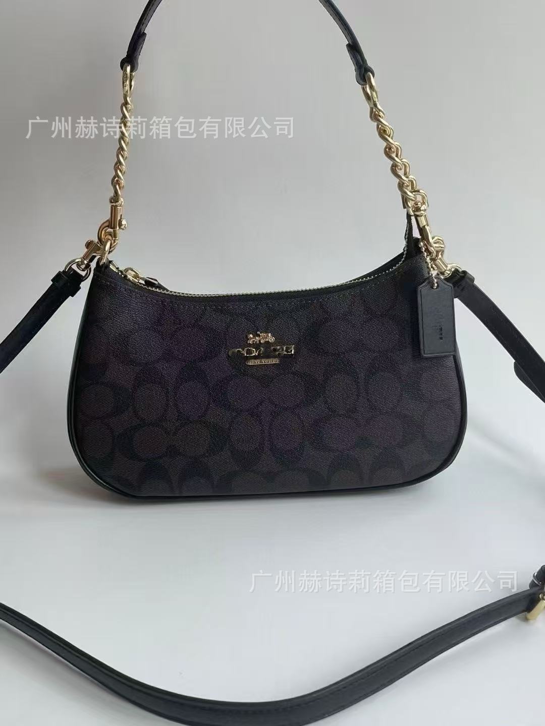 Black handbag with gold chain strap on a white background