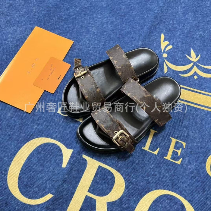 Pair of black sandals with brown straps on a blue surface with gold text