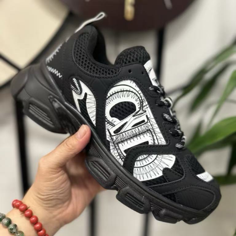 Black and white sneaker held by a hand with a blurred background