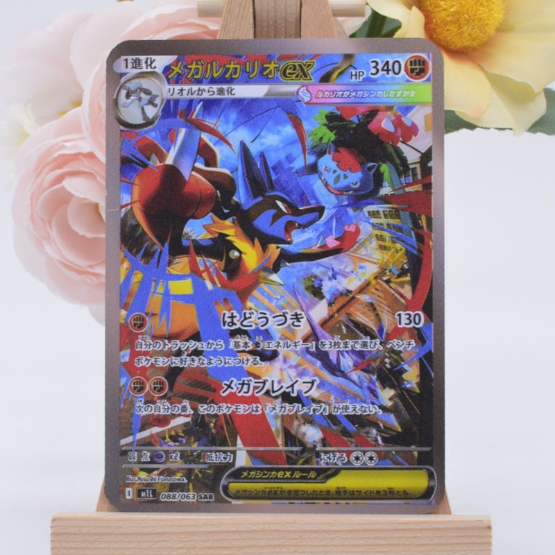 A Pokémon trading card featuring Groudon EX, displayed on a small wooden stand with soft pink and yellow flowers blurred in the background.