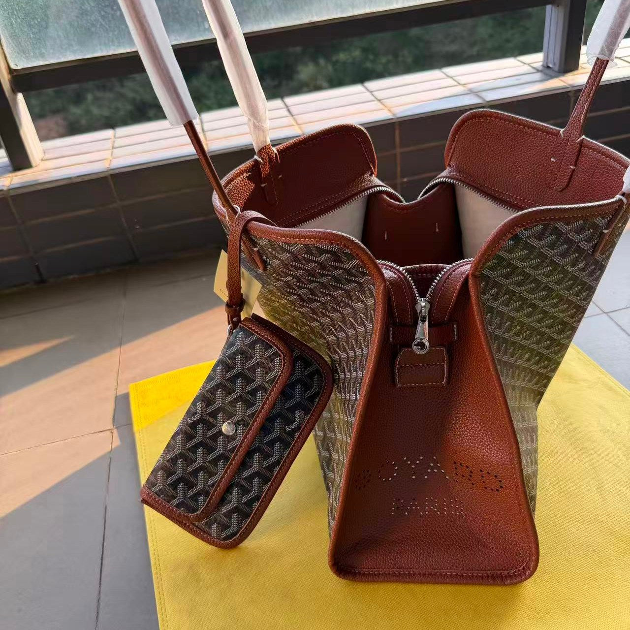 Brown leather handbag with patterned interior on a yellow surface