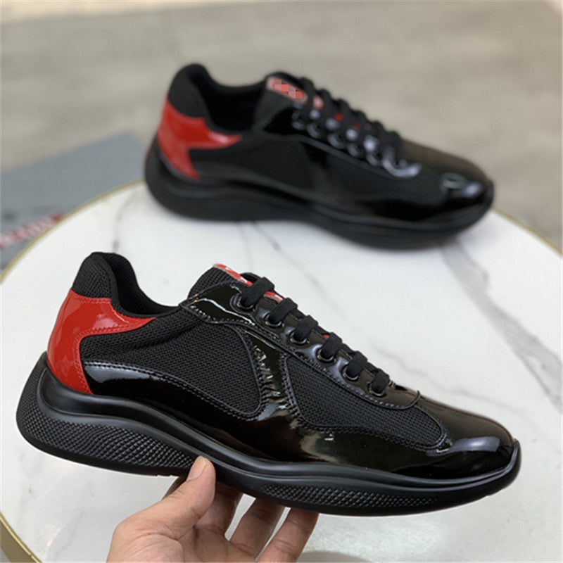 Black and red sneakers held by a hand on a light background