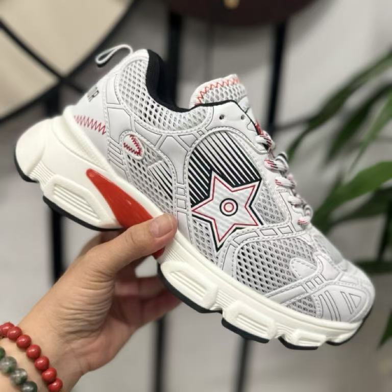 White sneaker with red accents held by a hand against a neutral background