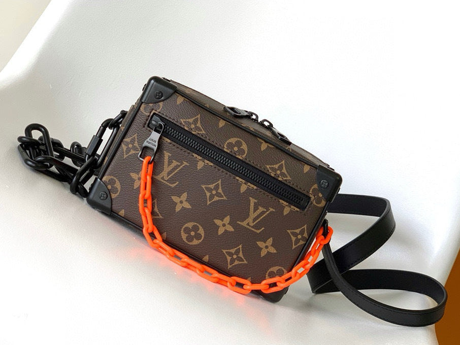 Designer bag with orange chain on a white surface
