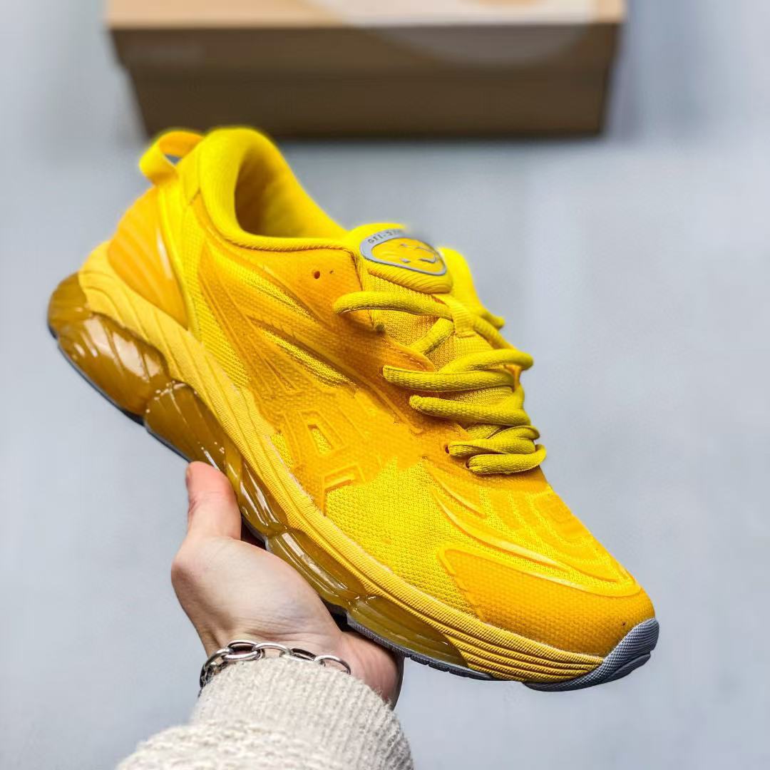 Yellow sneaker held by a hand against a neutral background