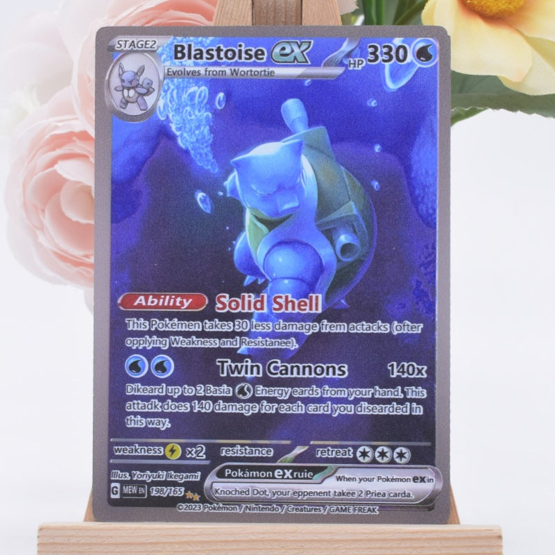 A holographic Pokémon EX trading card featuring Blastoise, displayed on a small wooden stand with blurred pink and yellow flowers in the background.