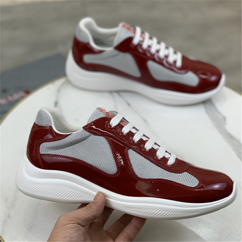 Red and white sneakers with a hand holding one shoe on a neutral background