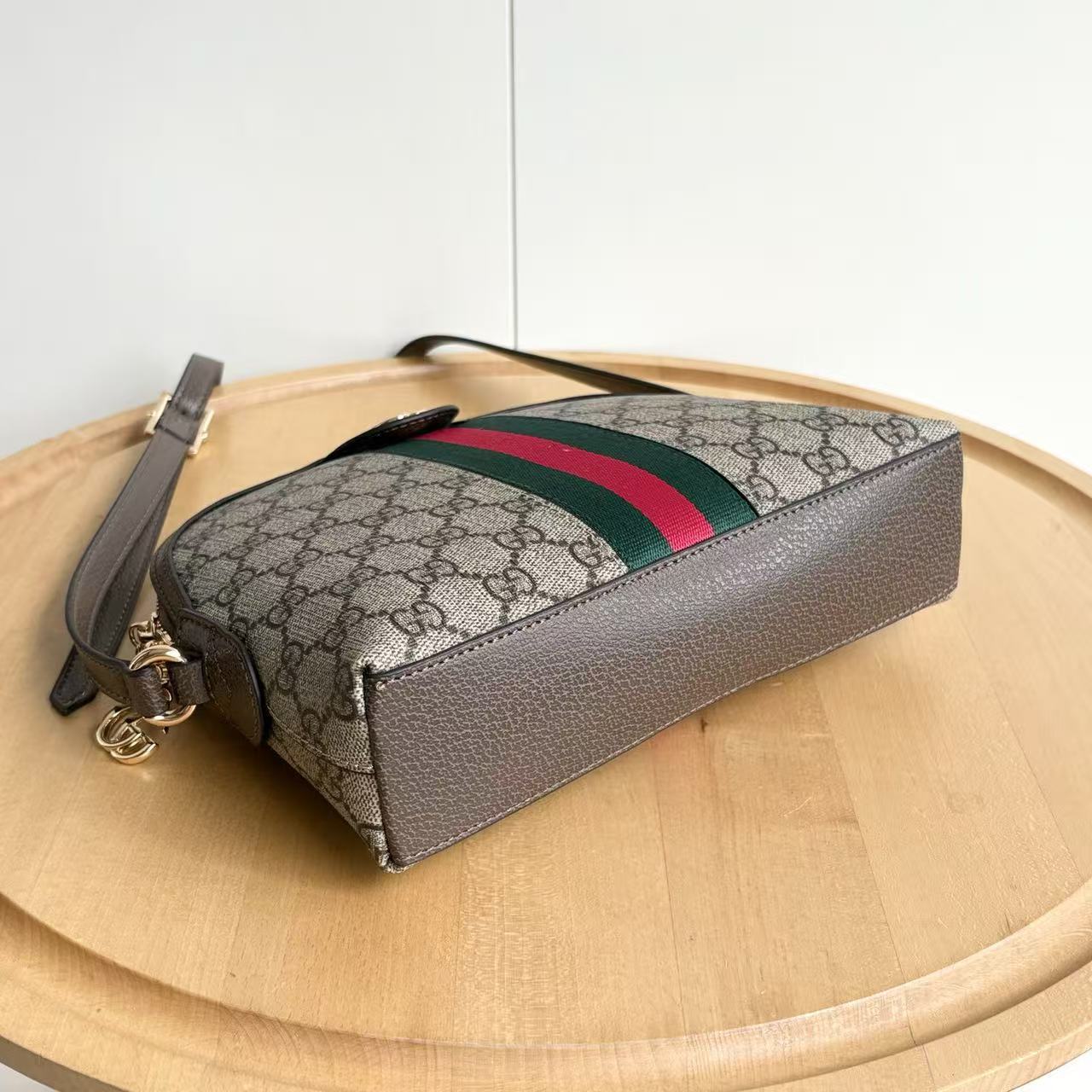 Designer handbag with patterned strap on a wooden surface