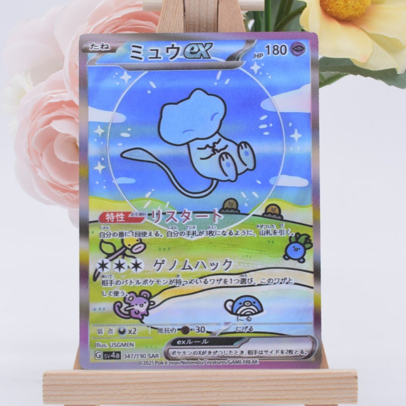 A holographic Pokémon trading card featuring the character Mew ex. in a blue and light blue illustration, displayed on a small wooden stand with decorative pink and yellow flowers in the background.