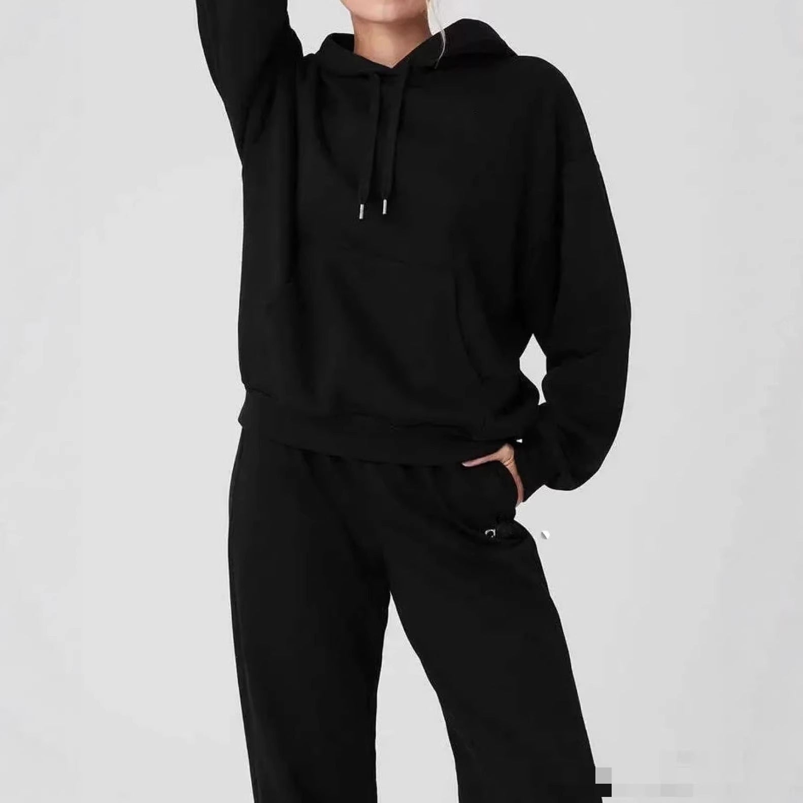 Person wearing a black hoodie and pants on a light gray background