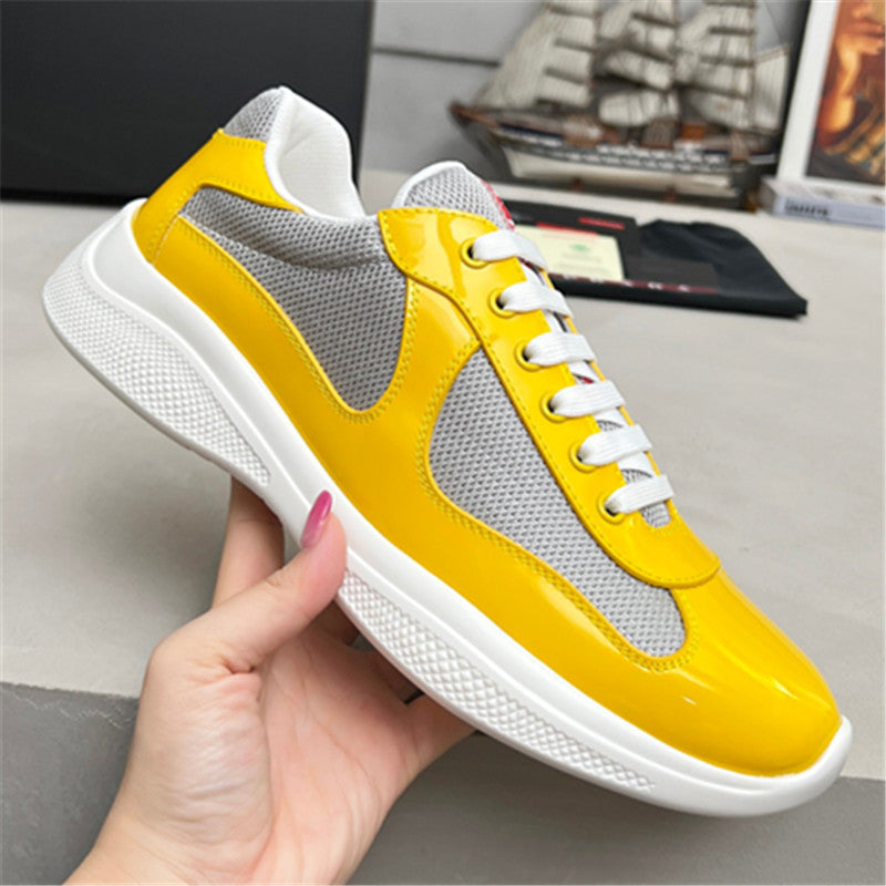 Yellow and gray sneaker with white sole held by a hand on a blurred background