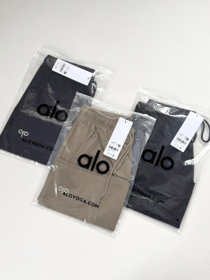 Three pieces of alo yoga clothing in clear packaging on a white background