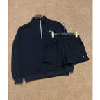 Black half-zip sweatshirt and shorts set on a beige carpet