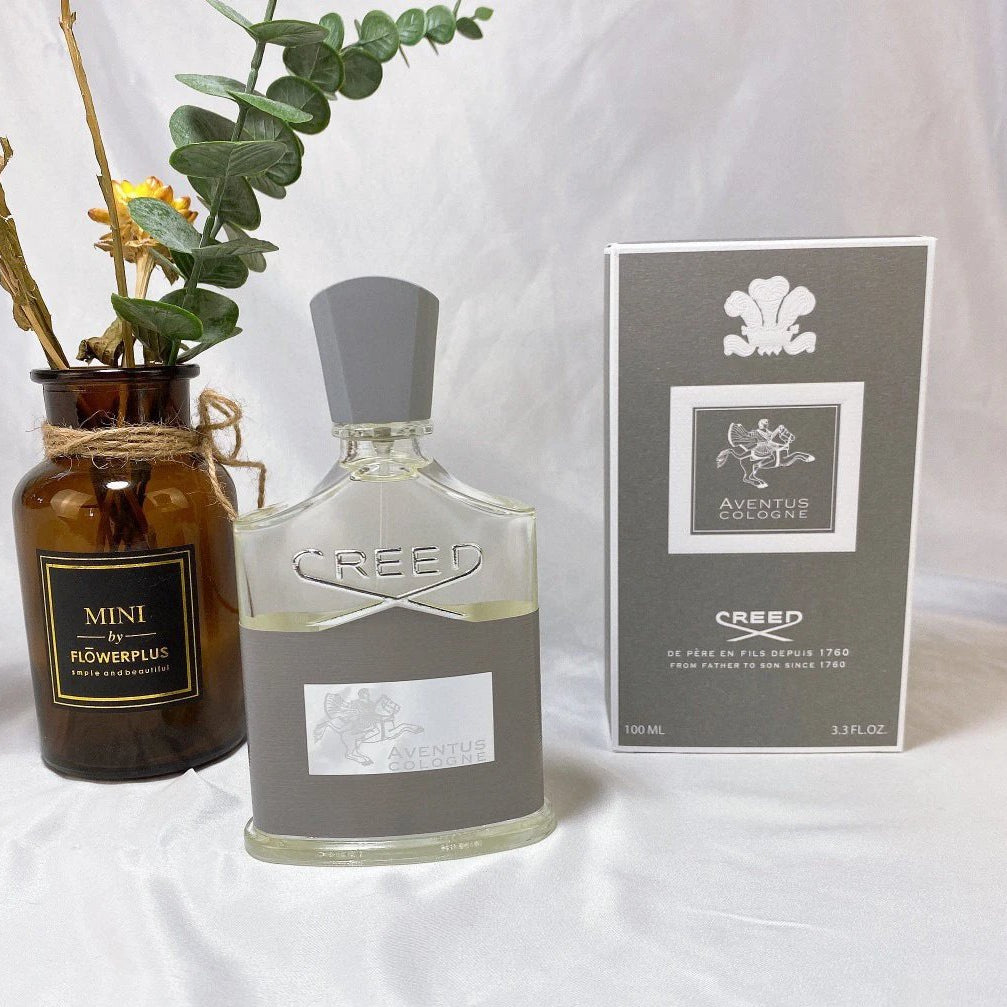 Creed cologne bottle with packaging and a vase on a white background