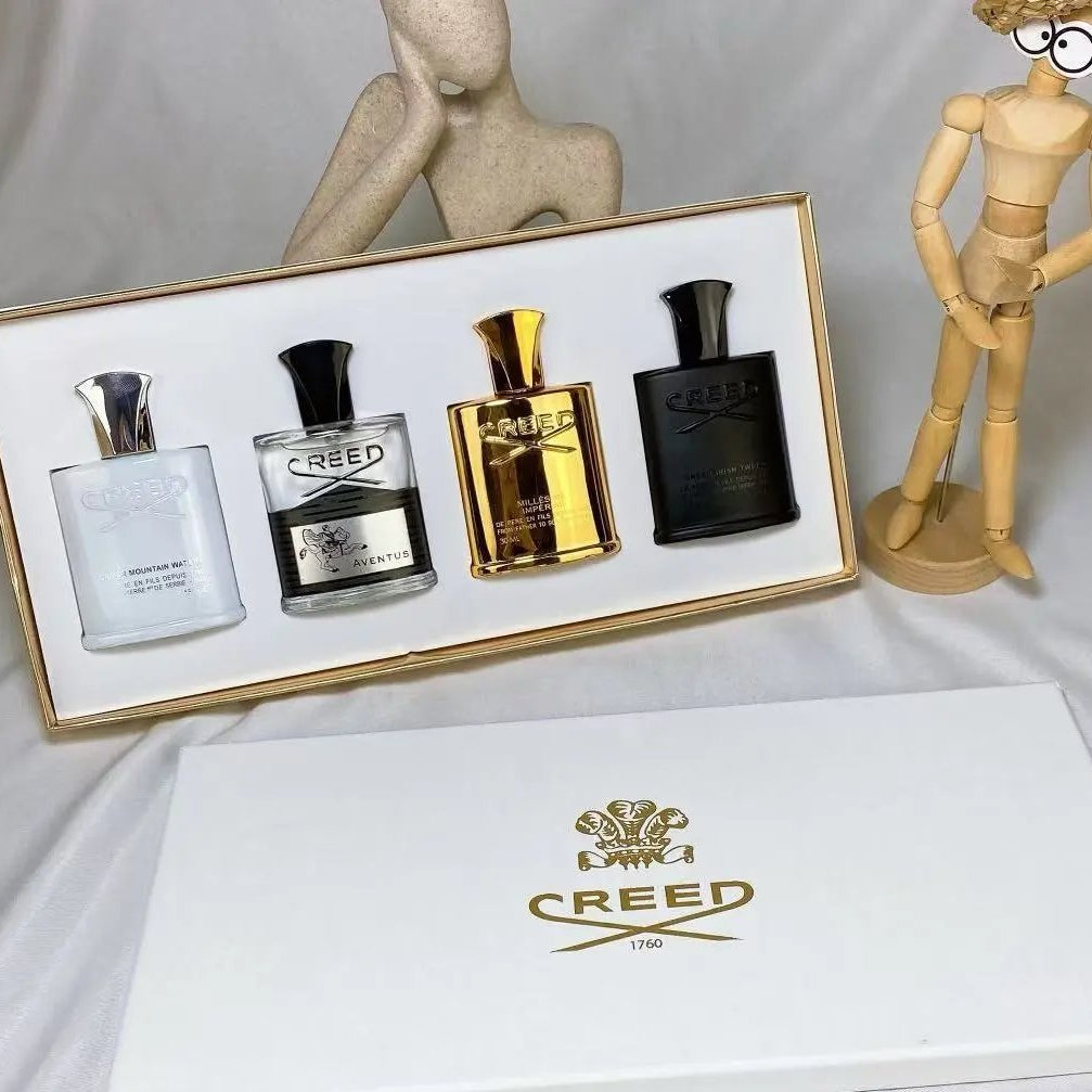 Set of Creed perfume bottles in a display case with a white box featuring the Creed logo.
