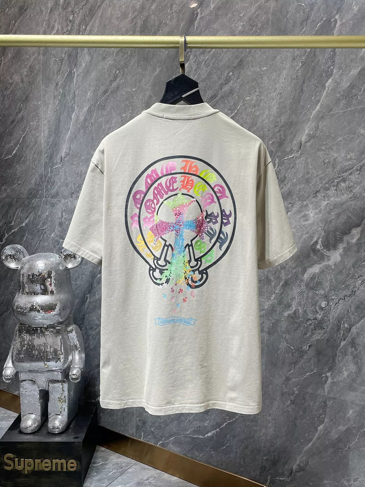 Beige t-shirt with colorful graphic design on a marble surface, featuring the Supreme brand.