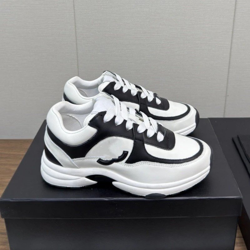 Black and white sneakers on a black box with a gray wall background