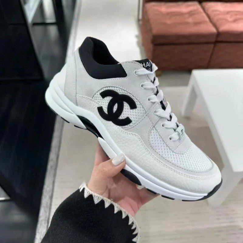 White sneaker with black accents held by a hand in an indoor setting