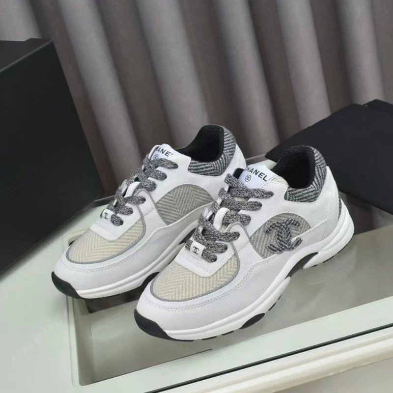 Pair of white sneakers with gray accents on a reflective surface.