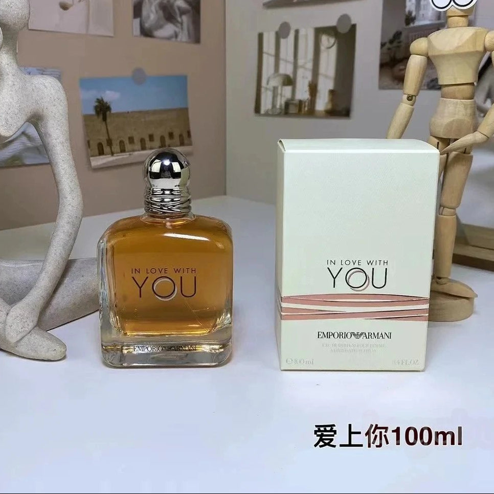 Perfume bottle and packaging labeled 'In Love with You' on a table with decorative items.