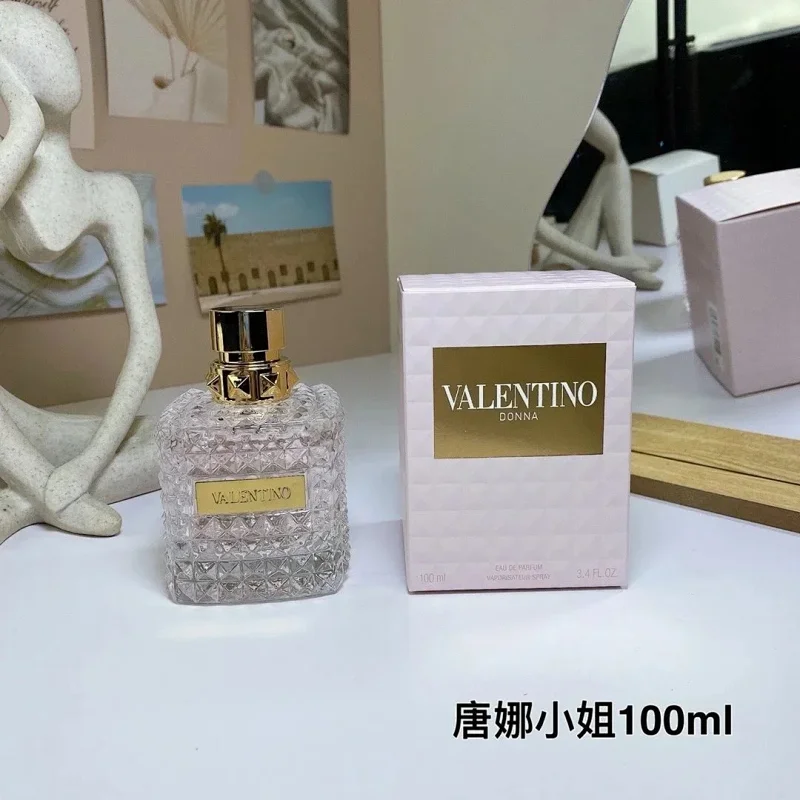 Valentino perfume bottle and packaging on a table with decorative items in the background
