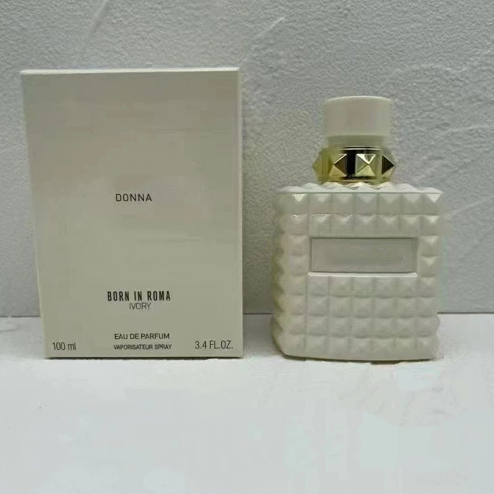 White quilted-patterned perfume bottle with decorative cap next to its packaging on a light gray background.