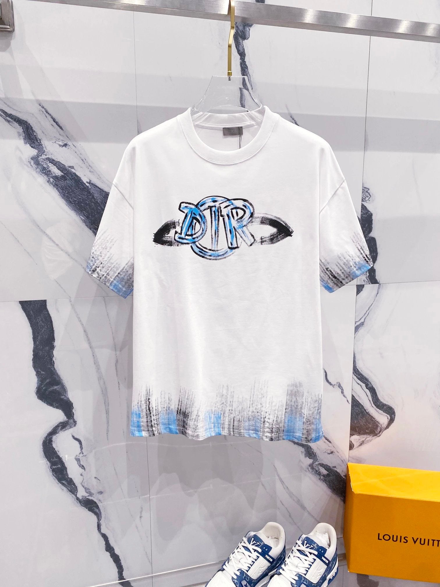 White t-shirt with blue tiger logo on a marble surface