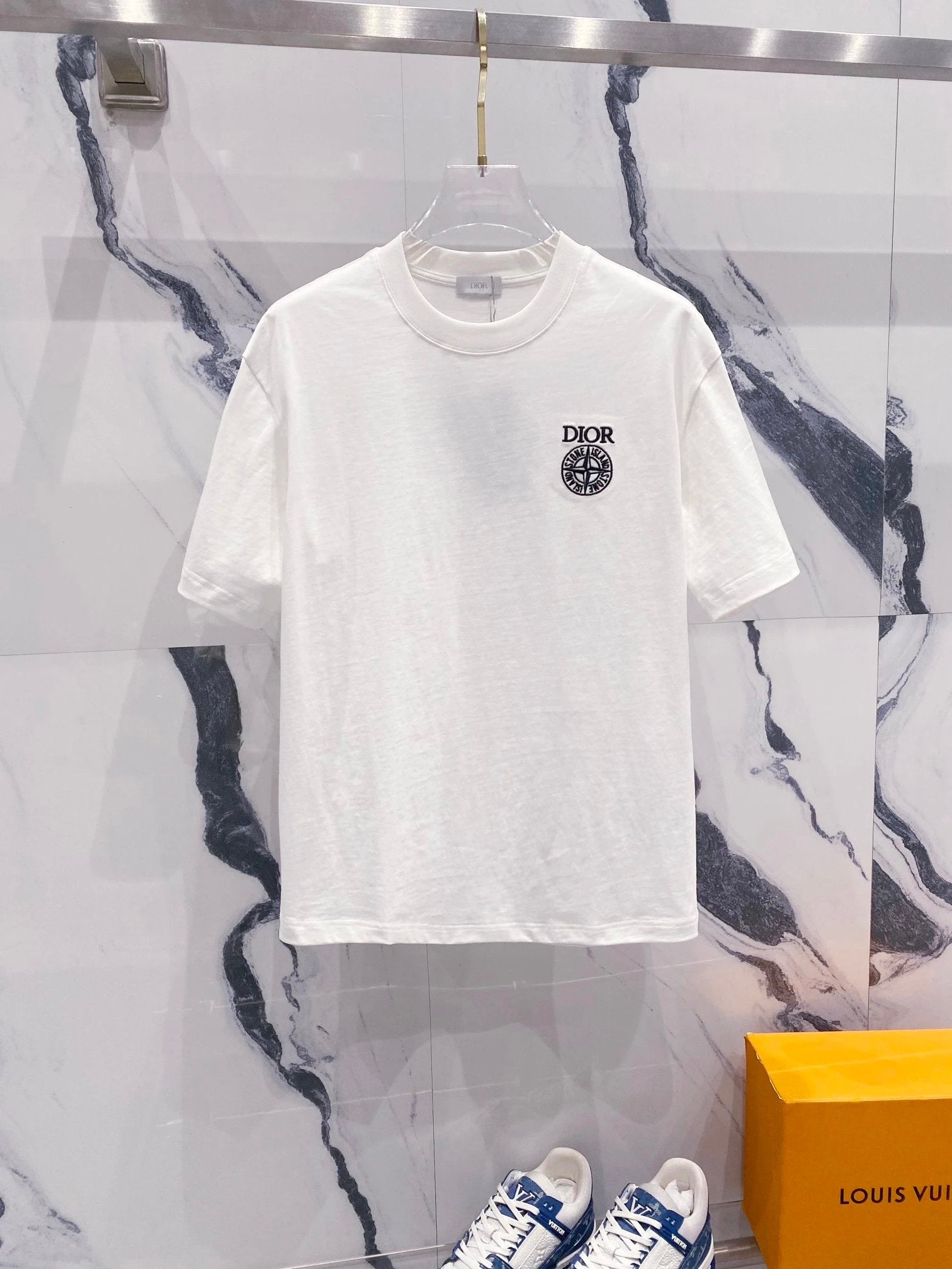 White t-shirt with a logo on a hanger against a marble wall background