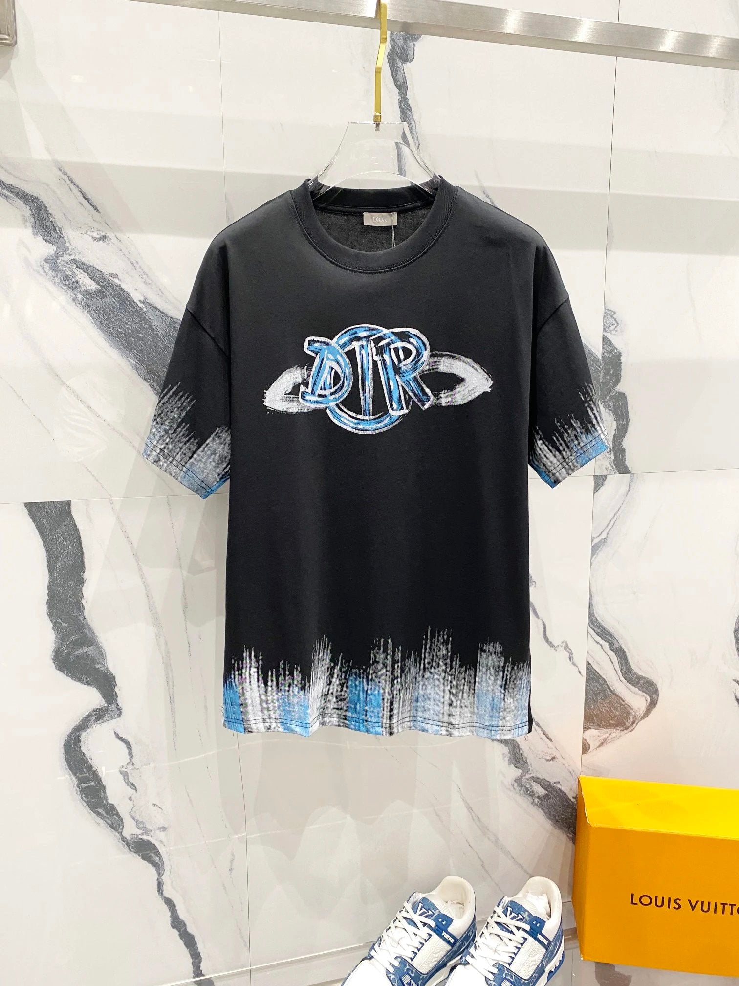 Black t-shirt with blue and white logo on a marble background