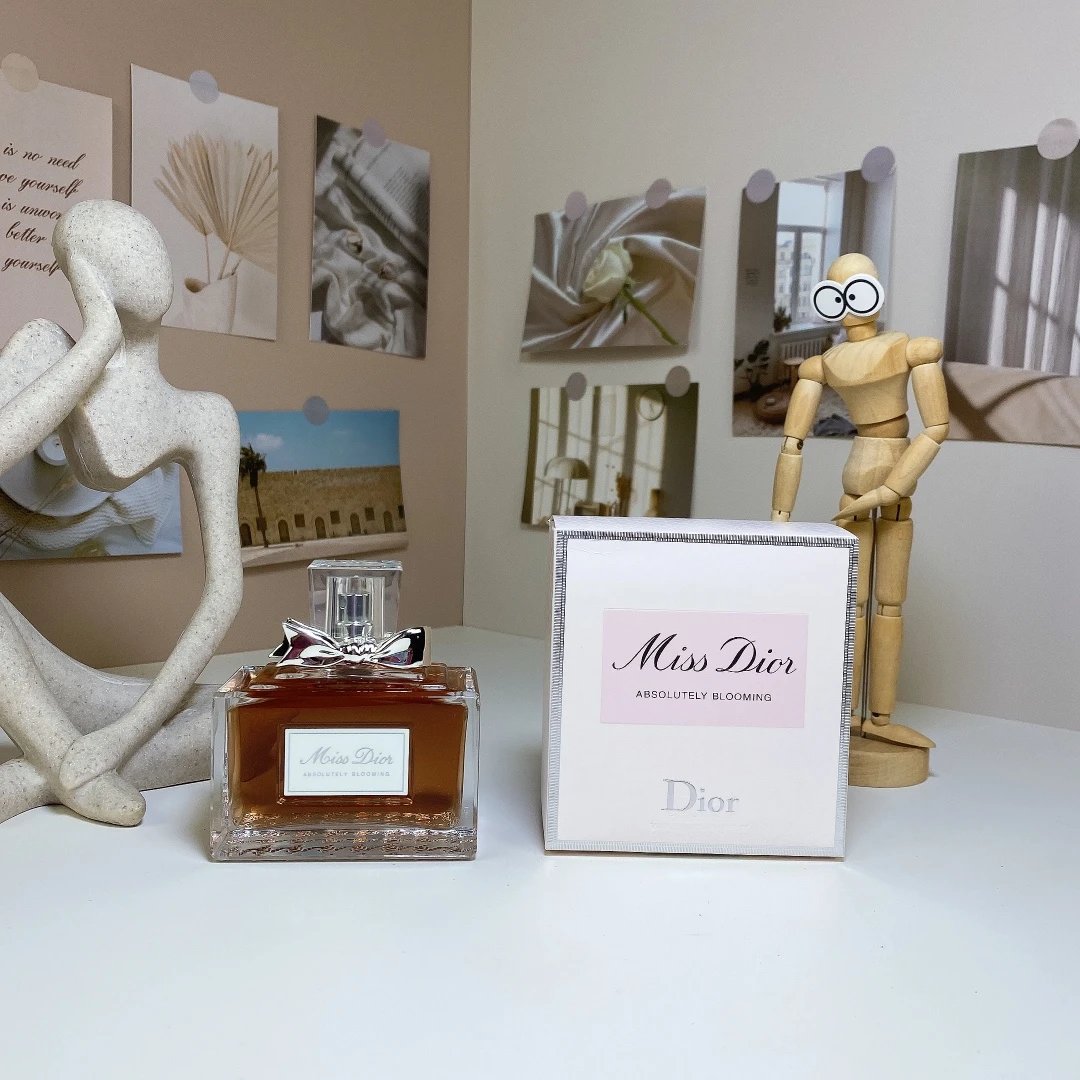 Dior Miss Dior perfume bottle and packaging on a table with decorative items in the background.