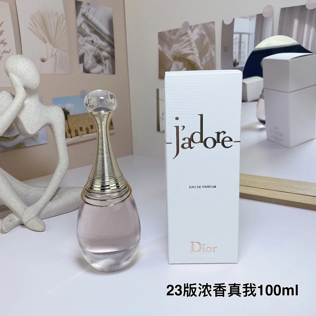 Dior Jadore perfume bottle and packaging on a white surface with decorative items in the background.