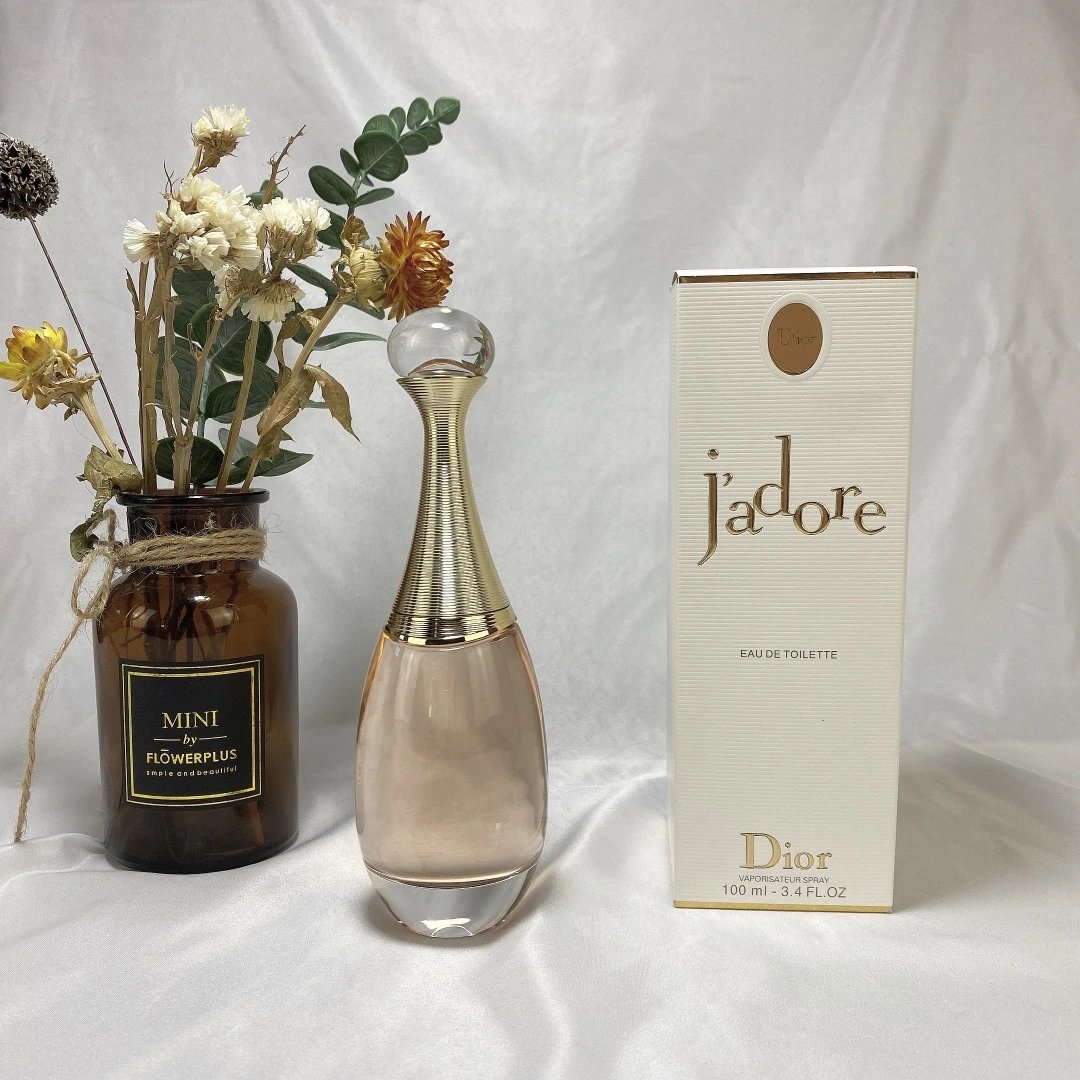 Dior Jadore perfume bottle and packaging with a vase of flowers on a white background