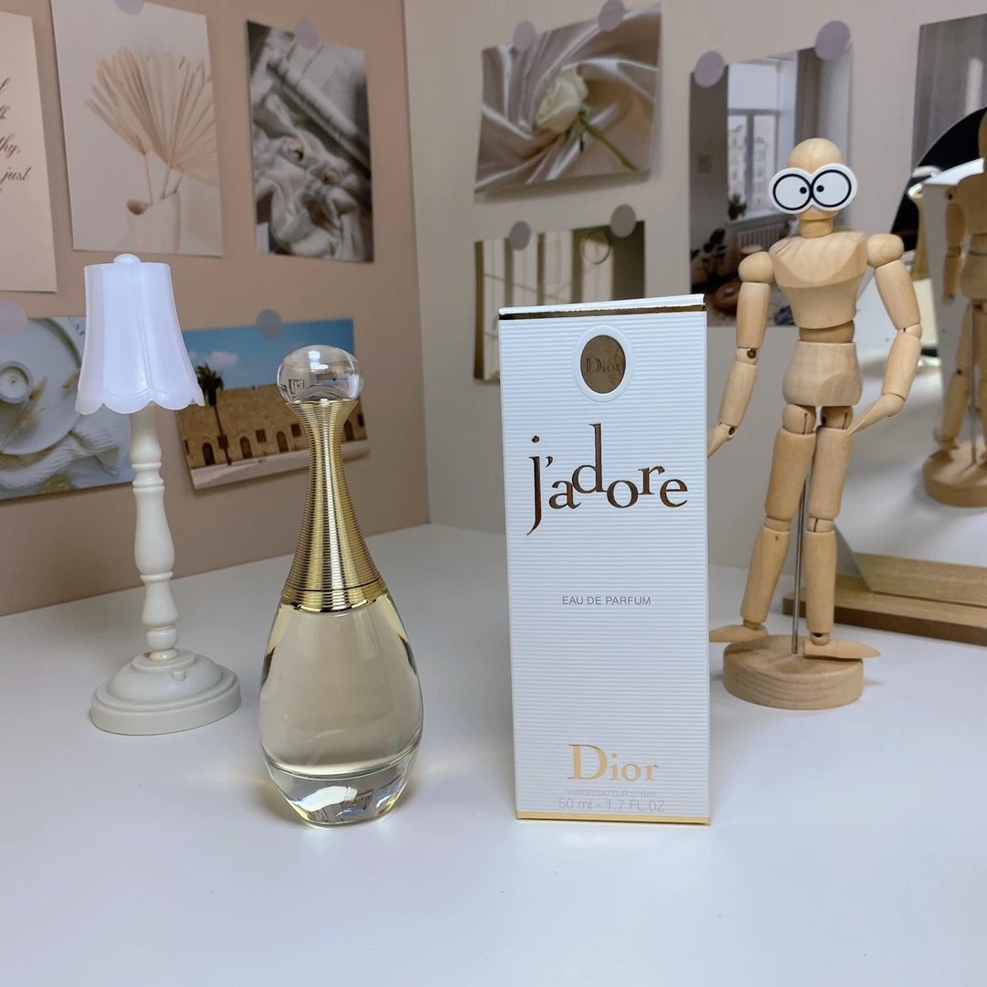 Dior Jadore perfume bottle and packaging on a table with decorative items.