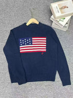 Navy blue sweater with American flag design on a gray surface