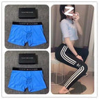 Blue Tommy Hilfiger boxer briefs with packaging and a person wearing black pants with white stripes.