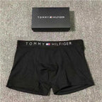 Black Tommy Hilfiger boxer briefs with a matching waistband on a textured surface.