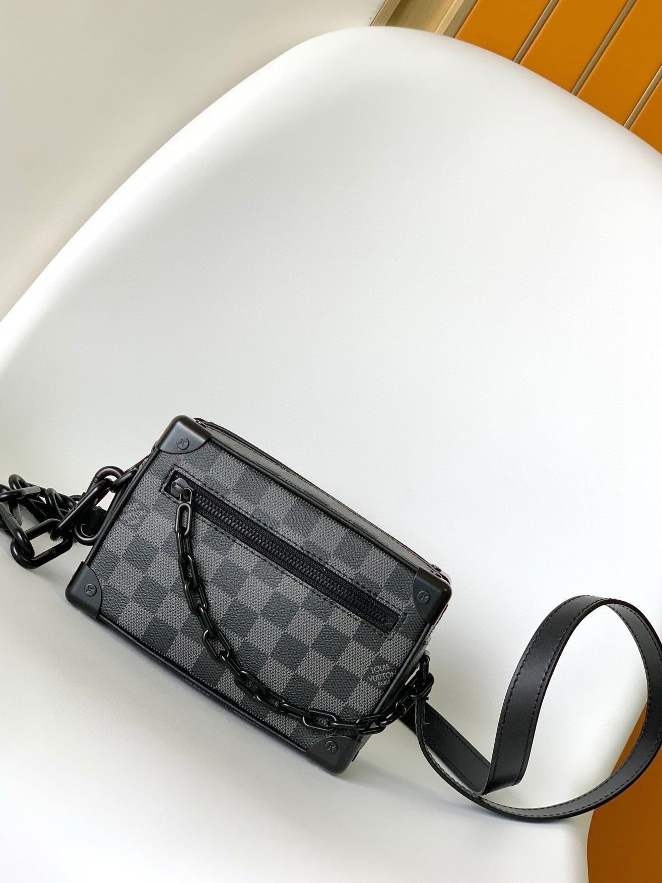 Black checkered handbag with a chain detail on a white surface