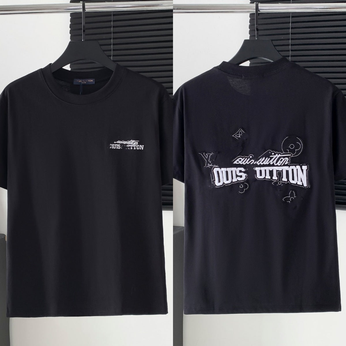 Black t-shirt with white branding on a hanger against a neutral background