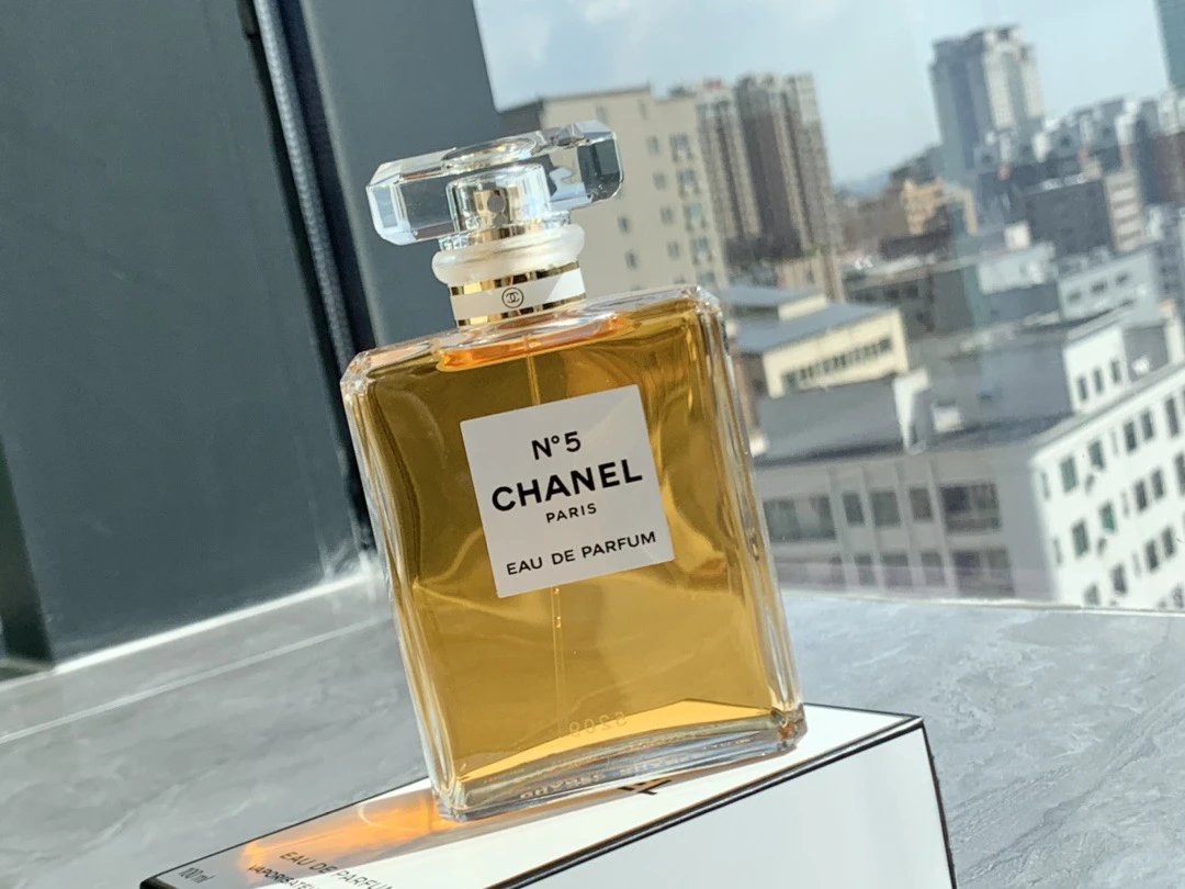 Chanel No. 5 perfume bottle with a cityscape in the background